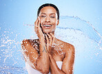 Water splash, woman and skincare for beauty, moisturizer or hydration by blue background wall. Black woman, skin model and splashes for cosmetics, health or dermatology wellness by cosmetic backdrop