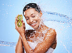 Water splash, kiwi and skincare of woman in studio isolated on a blue background. Healthcare, wellness and hygiene of female model from India with fresh and clean fruit for antioxidants or vitamin c.