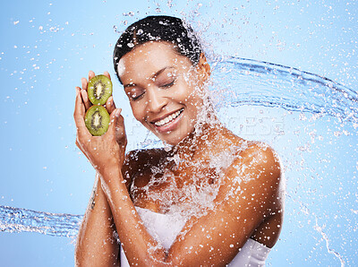 Buy stock photo Water splash, kiwi and skincare of woman in studio isolated on a blue background. Healthcare, wellness and hygiene of female model from India with fresh and clean fruit for antioxidants or vitamin c.