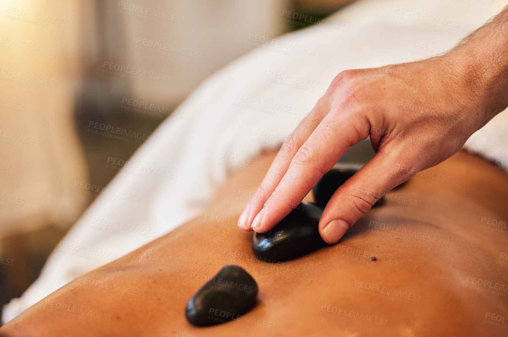 Buy stock photo Hot stone massage, spa and skincare for wellness, health and physical therapy to relax in luxury. Mind, body and spirit wellness with rock therapy on skin in closeup with oil, zen or natural cosmetic