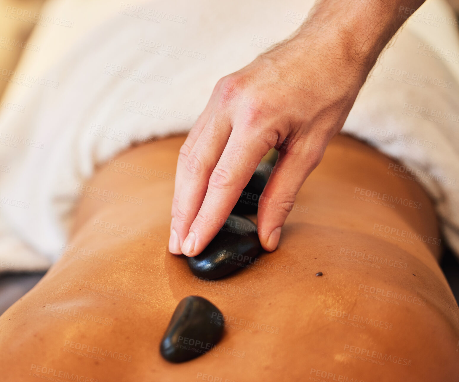 Buy stock photo Hands, back and rock massage at spa for stress relief, relaxation and spiritual zen treatment at a resort. Hand of therapist applying hot rocks or stone to skin for body care, healing or wellness