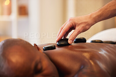 Buy stock photo Massage, therapy and hot stone for wellness and black man, massage therapist hand and wellness spa closeup. Skin, skincare and holistic health for stress relief and relax, self care and body care.