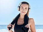 Fitness, music and portrait of woman at the beach for training, workout and health. Relax, radio and towel with girl and headphones after exercise for energy, sports and goals in the morning by sea