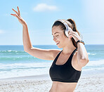 Headphones, beach and woman dance after workout, training or exercise. Freedom, energy and happy fitness female streaming audio, podcast or radio music at sandy seashore or ocean coast outdoors.