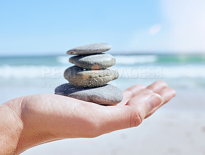 Buy stock photo Hand, stones pile and beach with a woman holding little rocks by the ocean for balance, wellness or zen. Nature, earth and mindfulness with a rock stock in the palm of a female on the sand by the sea