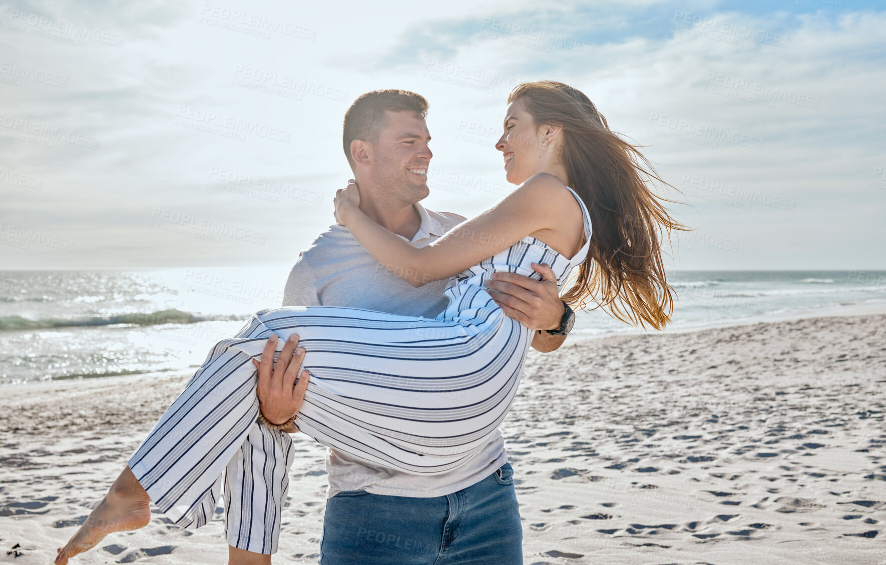 Buy stock photo Couple, love and carrying at beach, holiday and freedom on anniversary, romance and travel together in Hawaii. Man, woman and happy vacation, smile and support in marriage relationship at the ocean
