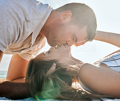 Buy stock photo Love, romance and couple kiss at beach on summer holiday, vacation and weekend together. Relationship, travel and young man and woman kissing laying on sand by ocean, seaside and nature to relax