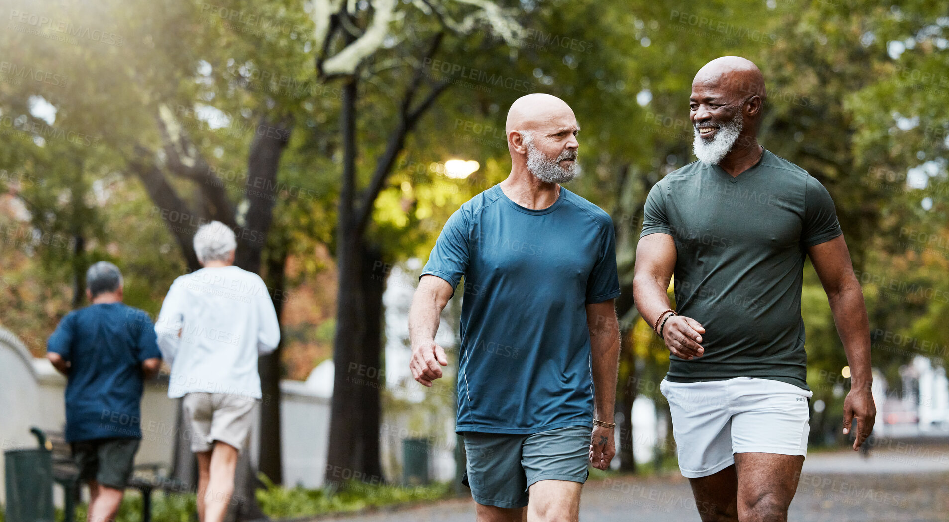 Buy stock photo Fitness, exercise and men walking together at community park while talking and doing cardio training outdoor in nature. Diversity, friends and senior man and accountability partner on a wellness walk