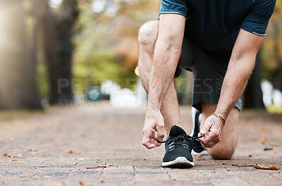 Buy stock photo Shoes, fitness and runner with a sports man tying his laces before a run in the park for exercise. Running, training and workout with a male athlete fastening his shoelaces during cardio or endurance