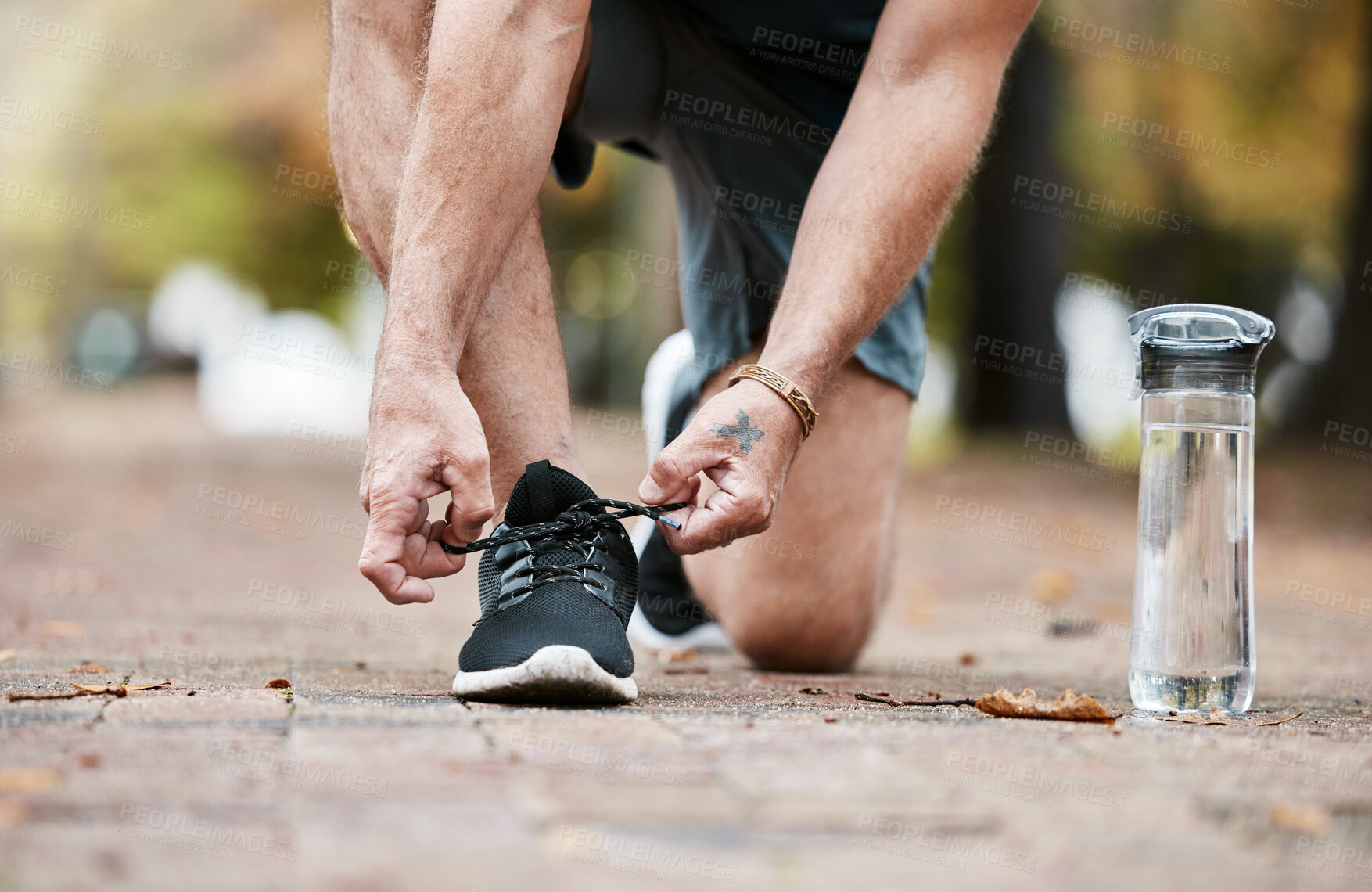 Buy stock photo Fitness, exercise and running shoes while tying shoelace on ground with water bottle for cardio workout or training. Hands of man with sneakers outdoor for run and performance for health and wellness