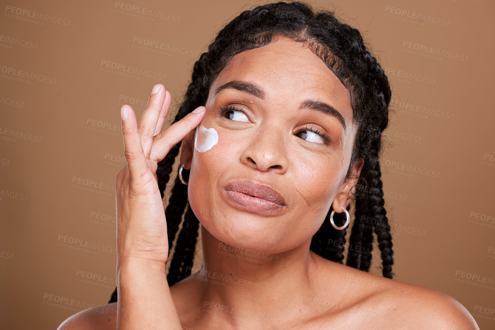 Buy stock photo Black woman, skincare and facial moisturizer for beauty cream, makeup or cosmetics against a brown studio background. African American female applying lotion to smooth or hydrate skin for treatment