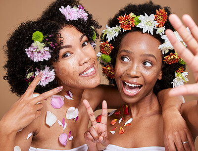 Buy stock photo Beauty, friends and flowers with a model black woman pair in studio on a brown background for skincare. Nature, luxury and relax with an attractive young female and friend posing for natural wellness