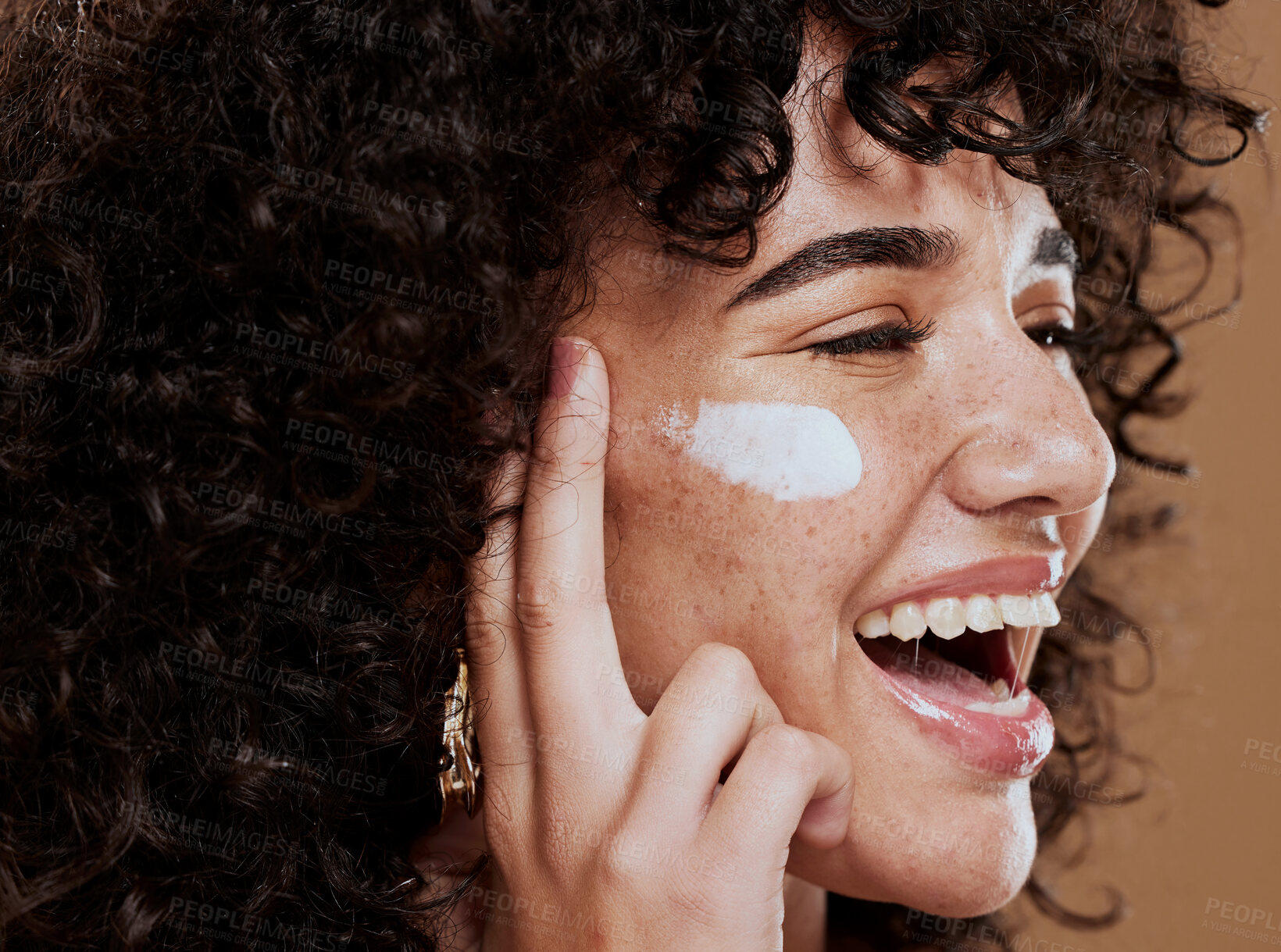 Buy stock photo Cream, woman and skincare for wellness, natural beauty and confident on brown studio background. Cosmetics, female and girl with lotion, smooth face and organic facial with smile, happy and freckles.