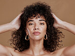 Hair care, black woman and portrait with curly hair, beauty and wellness by cosmetics background. Hair, model and jewelry earrings with cosmetic skin glow with makeup, gold jewellery and radiant face