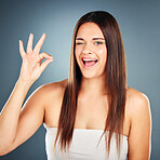 Ok hand sign, woman and happy for success with face wink or advertising marketing in studio. Influencer approval, beauty cosmetics and campaign approval, yes or good job against blue wall background