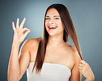 Hand, hair and perfect with a model woman in studio on a blue background for natural haircare satisfaction. Gesture, sign and hair care with an attractive young female proud of her strong hairstyle