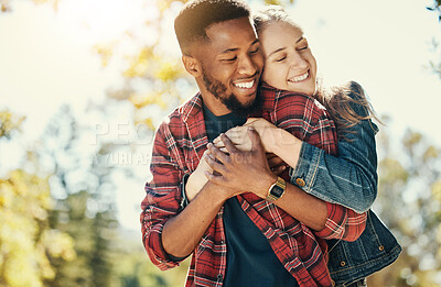 Buy stock photo Love, nature and diversity couple hug on outdoor journey together, romantic park date and quality time fun. Sunshine flare, leaf and summer freedom peace for happy gen z woman and black man bonding