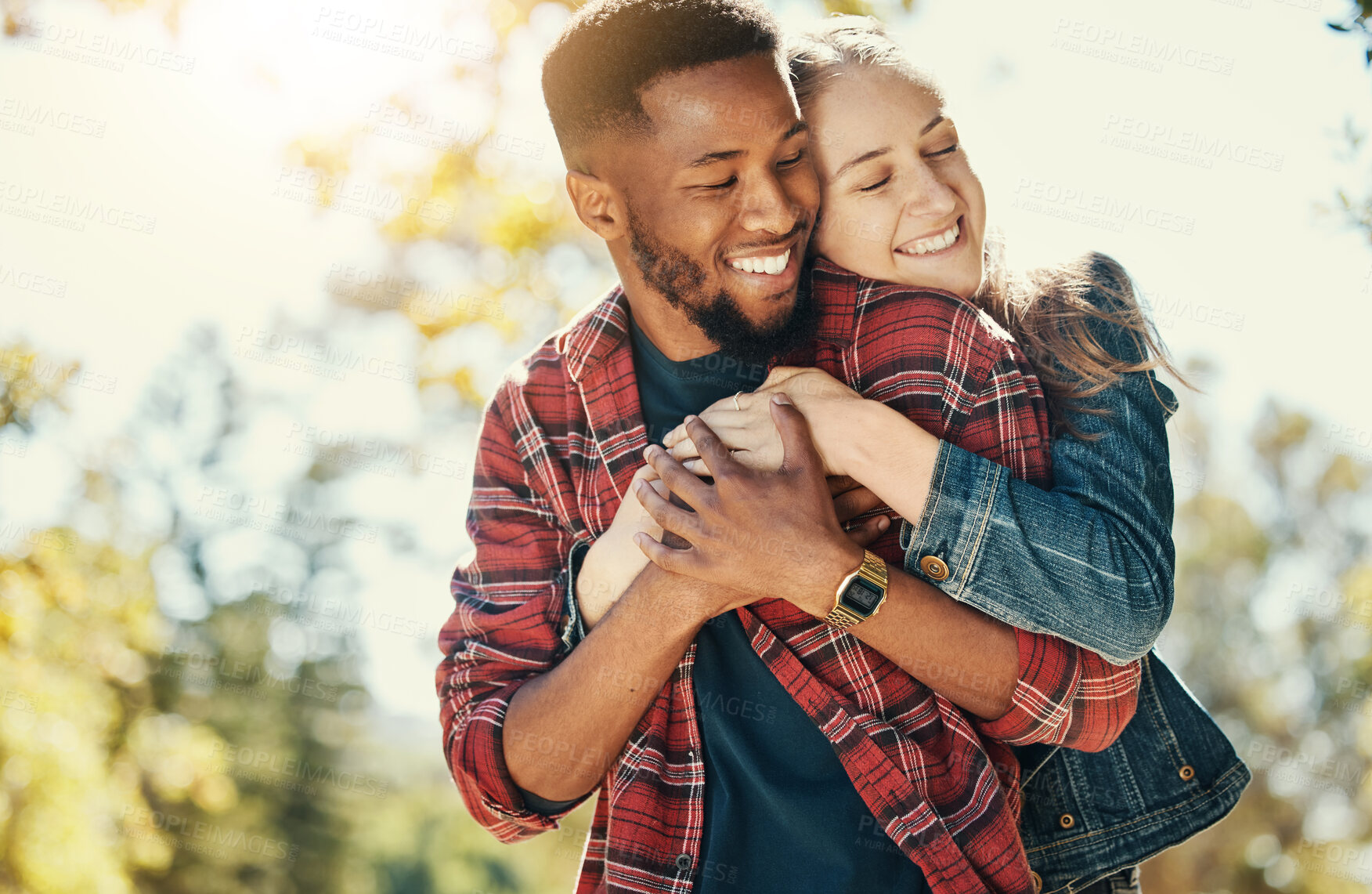 Buy stock photo Love, nature and diversity couple hug on outdoor journey together, romantic park date and quality time fun. Sunshine flare, leaf and summer freedom peace for happy gen z woman and black man bonding