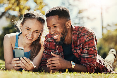 Buy stock photo Interracial, couple and phone social media in park to relax, bond and smile together in Los Angeles. Technology, streaming and happy people enjoy summer in nature with mobile app entertainment.