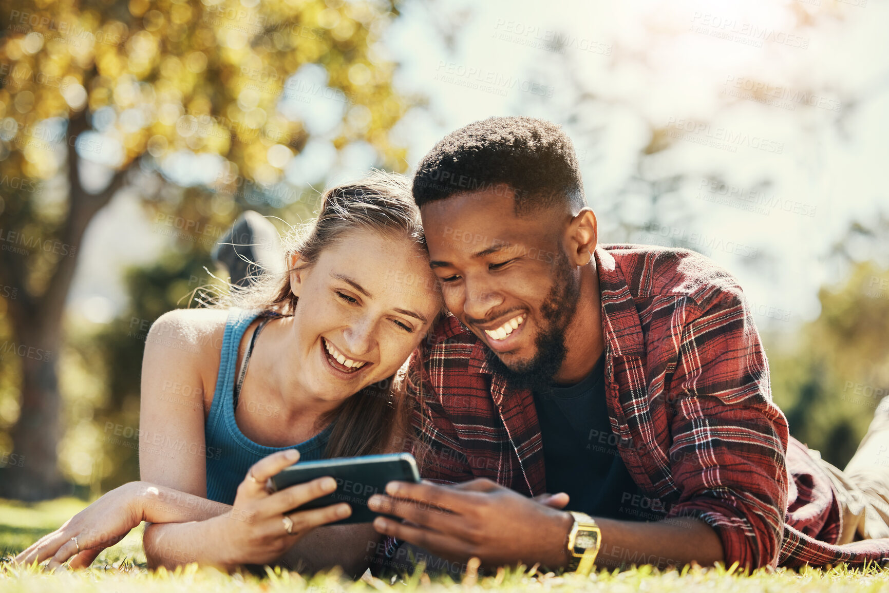 Buy stock photo Phone, park and relax diversity couple streaming online comedy movie, funny subscription video or romantic show. Love, freedom peace and bonding black man and woman watch social media meme on date