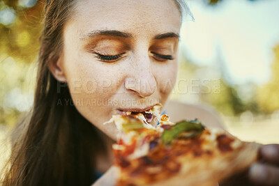 Buy stock photo Eating, pizza and hungry with a woman biting a slice of fast food outdoor in a park or garden on the weekend. Food, bite and lunch with a young female enjoying a snack outside for her hunger
