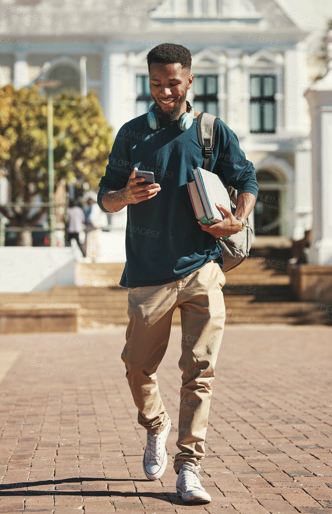 Buy stock photo University, education and phone with a black man student typing a text message while carrying books. Contact, study and scholarship with a male pupil walking to class at college for development