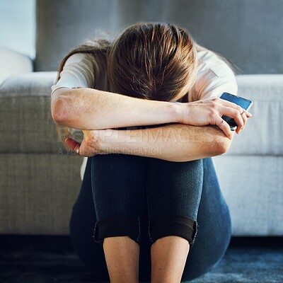 Sad, depression and woman with phone in living room home after break up message, cyber bullying victim or grief. Mental health, anxiety or depressed female holding 5g mobile smartphone alone in house