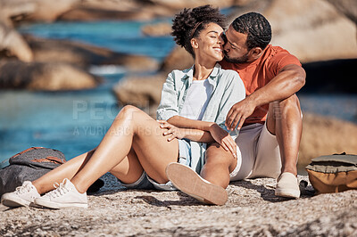 Buy stock photo Love, kiss and happy couple on a rock at the beach relaxing, bonding and embracing while on vacation. Happiness, smile and young man and woman by the ocean on a romantic, calm and zen seaside holiday