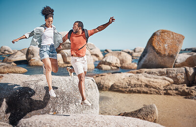 Buy stock photo Black couple, fitness and beach while on vacation taking a jump or leap from a rock for travel, adventure and exercise in summer. Happy man and woman together at sea for quality time on holiday