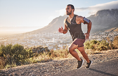 Buy stock photo Fitness, sports and man running on mountain with city background doing marathon training. Speed, endurance and athlete with headphones listening to music doing exercise, workout and sport performance