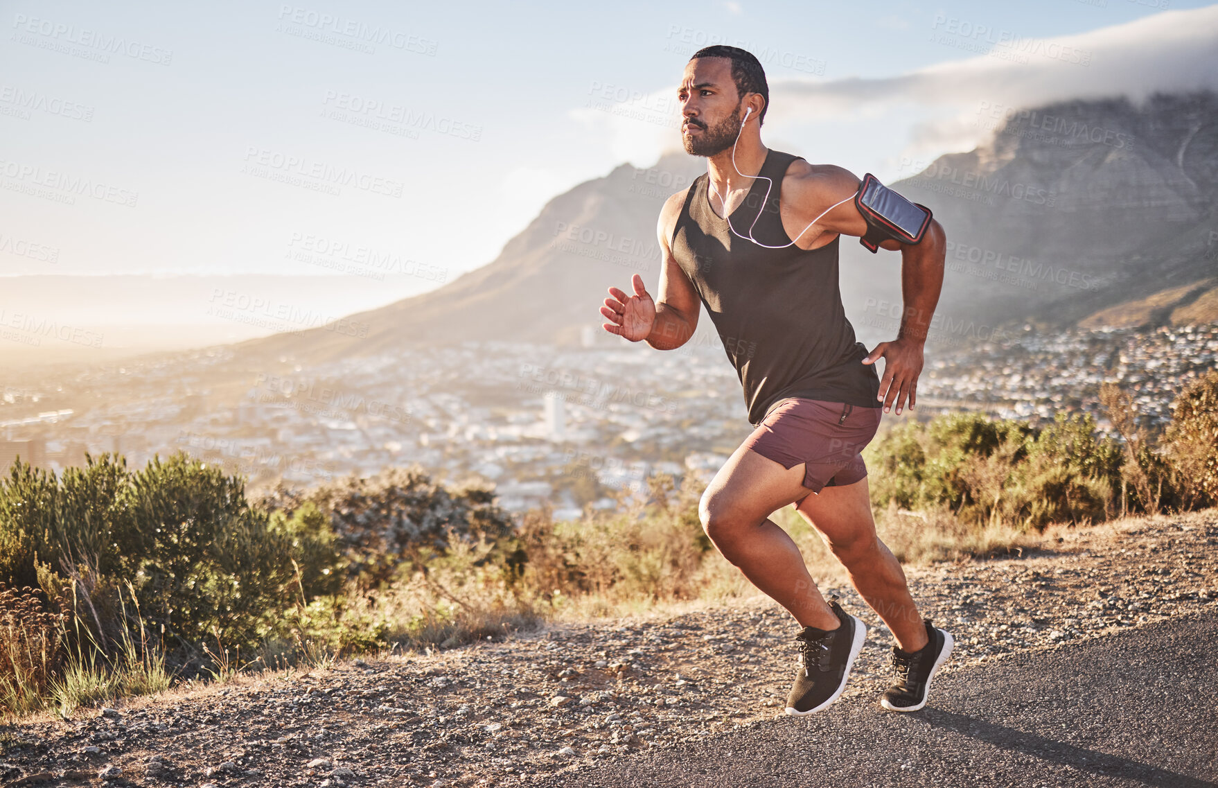 Buy stock photo Fitness, sports and man running on mountain with city background doing marathon training. Speed, endurance and athlete with headphones listening to music doing exercise, workout and sport performance