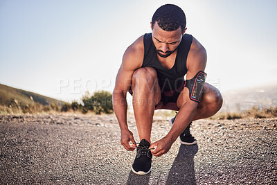 Buy stock photo Fitness, tie and shoes of a man on a road for running, cardio workout or training for a marathon in summer. Focus, wellness and healthy sports athlete runner tying footwear laces to start exercise