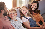 Happy, love and parents on a sofa with their children talking, laughing and bonding in the living room. Happiness, smile and family in comic or funny conversation while relaxing on the couch at home.