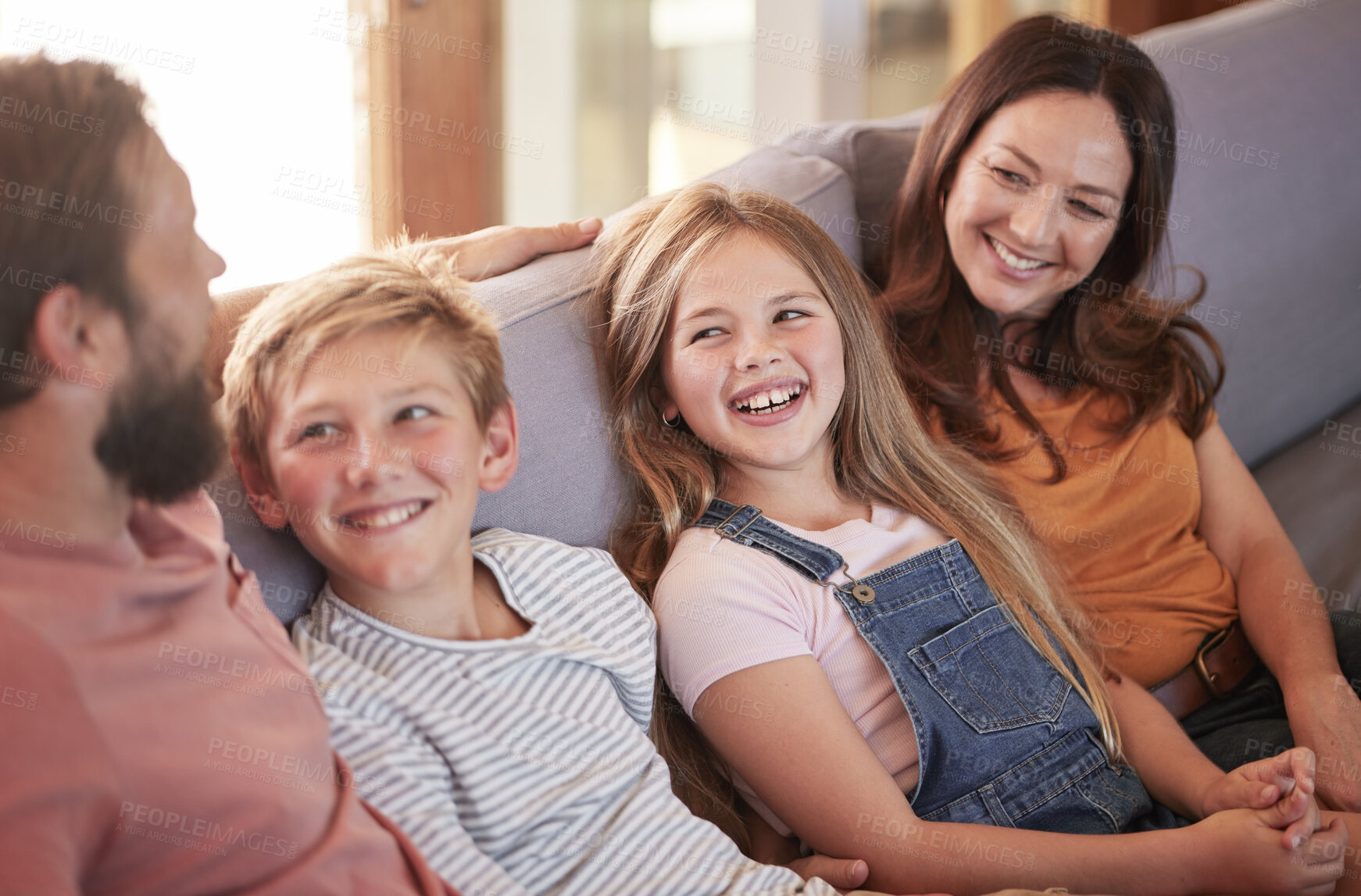 Buy stock photo Happy, love and parents on a sofa with their children talking, laughing and bonding in the living room. Happiness, smile and family in comic or funny conversation while relaxing on the couch at home.