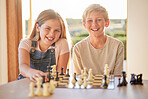 Kids, chess and board game in portrait in house for learning, strategy and happy development together. Children, girl and brother with smile, happiness and family games at table in home living room