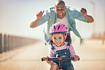 Excited father teaching girl to ride a bike in sunshine, summer fun and beach promenade outdoors. Happy kid, learning and riding bicycle with help from dad, parent and safety for healthy development 