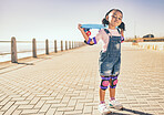 Young girl, skateboard and ocean walk of a child holding a board to skate by the beach. Kid portrait of a skateboarder with a grunge pose ready for summer activity, freedom and outdoor youth fun