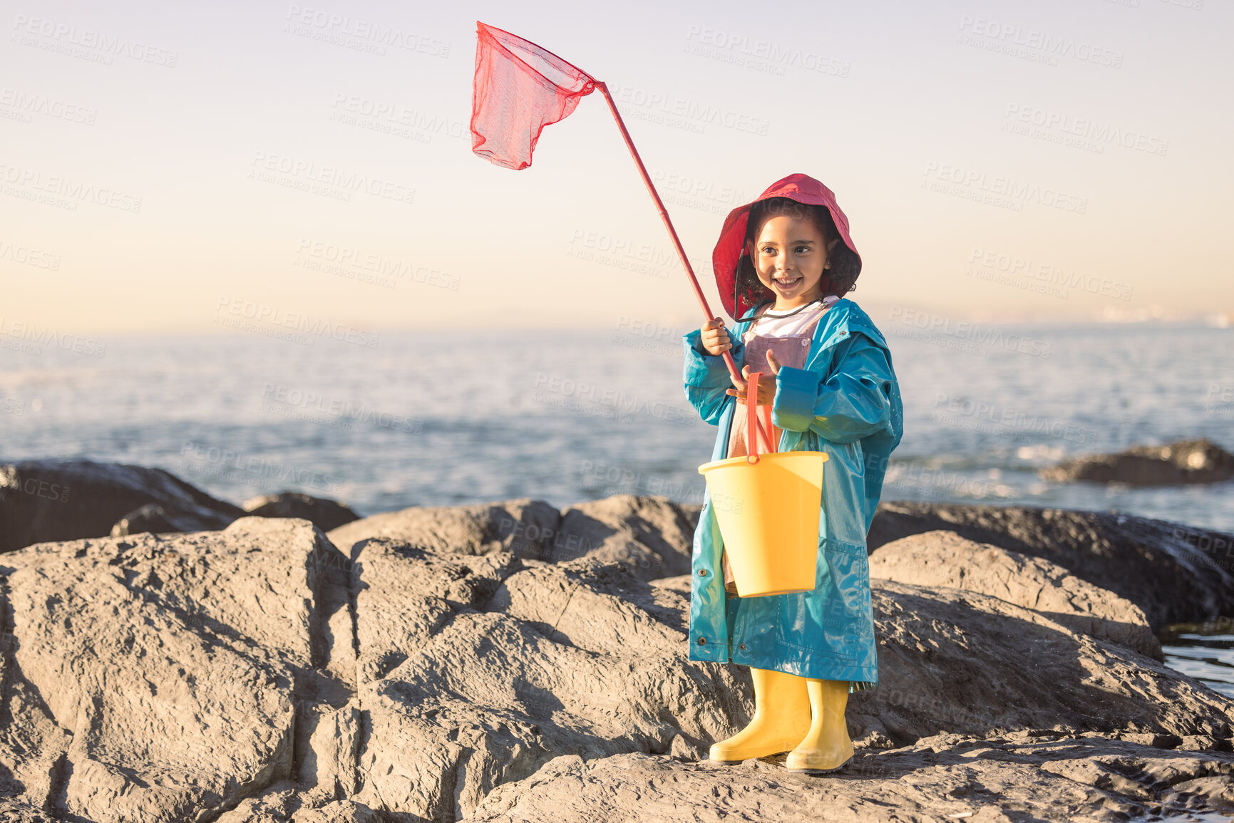 Buy stock photo Child, girl or kid fishing net or bucket by beach rock pools, ocean or sea for salt water shrimp, muscles or crabs on summer holiday. Smile, happy or youth and fisherman equipment in Brazilian nature