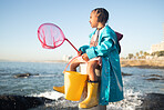 Girl, beach and fishing net with bucket, water and rock pool for outdoor adventure with boots, smile and ocean. Black child, sea and happy for fish, waves or sea in nature, learning and sunshine