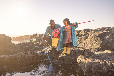 Buy stock photo Beach, fishing and dad and kid bonding for a learning seaside holiday in summer at sunset. Little girl, father and net or bucket to catch fish in the ocean for marine conservation and bond