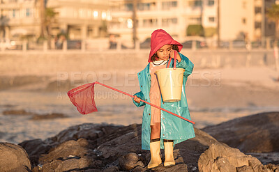 Buy stock photo Beach, fishing and girl with a net and bucket standing on a rock by the ocean on vacation. Outdoor, nature and child at the seaside to catch fish in the sea water for an adventure while on holiday. 