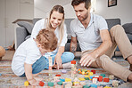 Learning, happy and family with building blocks on living room floor for child development skills. Mother, dad and young child on carpet with toys in family home for bonding, teaching and fun.

