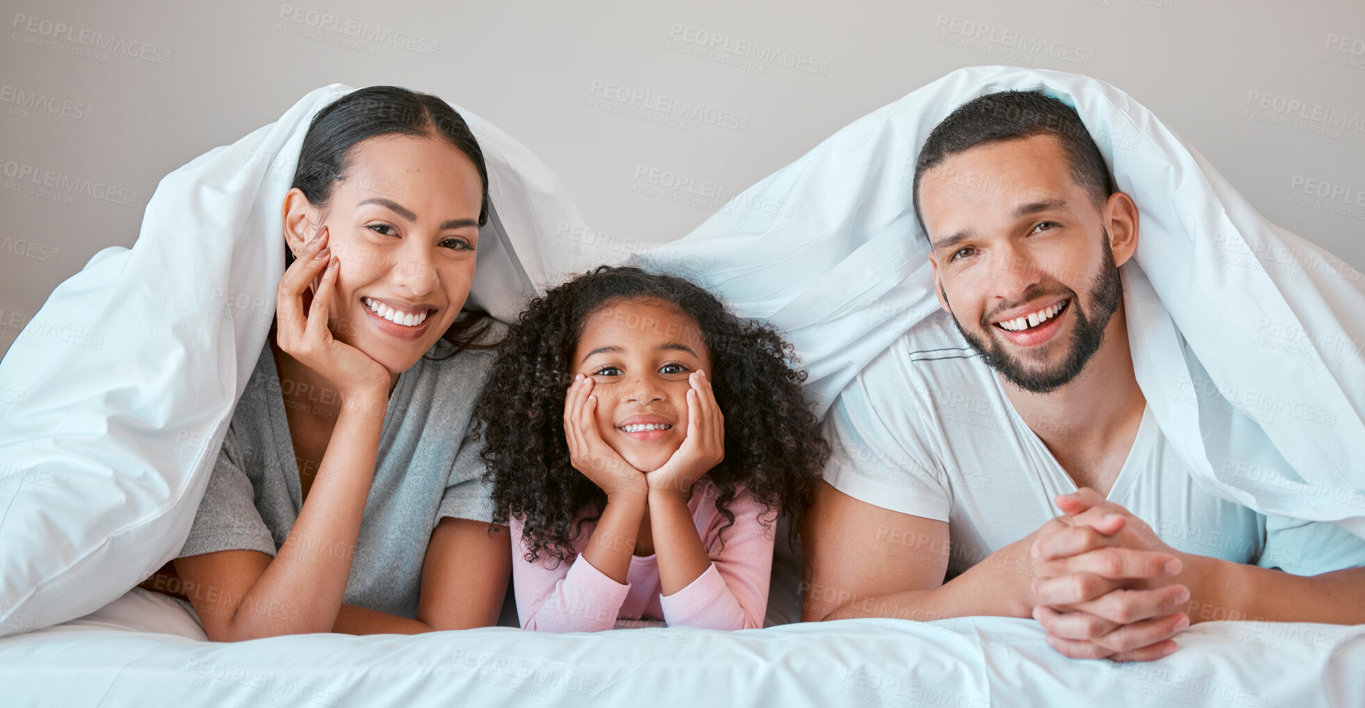 Buy stock photo Relax, happy and girl with her parents in bed for security, love and safety under blanket in their family home. Support, smile and portrait of a child with her mother and father in the bedroom