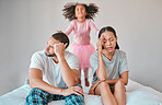 Stress, divorce and couple with a child on the bed with her parents in an argument or disagreement. Divorce, break up and young angry mother and father with girl jumping in the bedroom at their home.