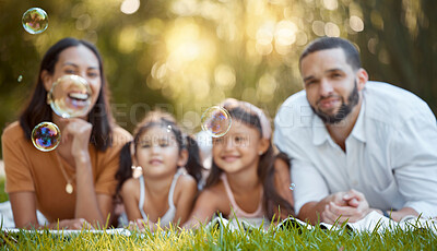 Buy stock photo Bubbles, family and relax on grass at park, nature or outdoors on summer vacation. Happy portrait, smile and care of parents and girls bonding, enjoying quality time together and having fun in garden