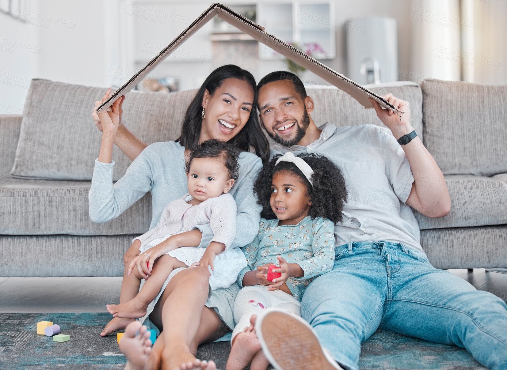 Buy stock photo Happy family, new house and cardboard roof in living room, mortgage loan and investment security for future. Real estate, insurance and property cover for new homeowners, excited parents and children