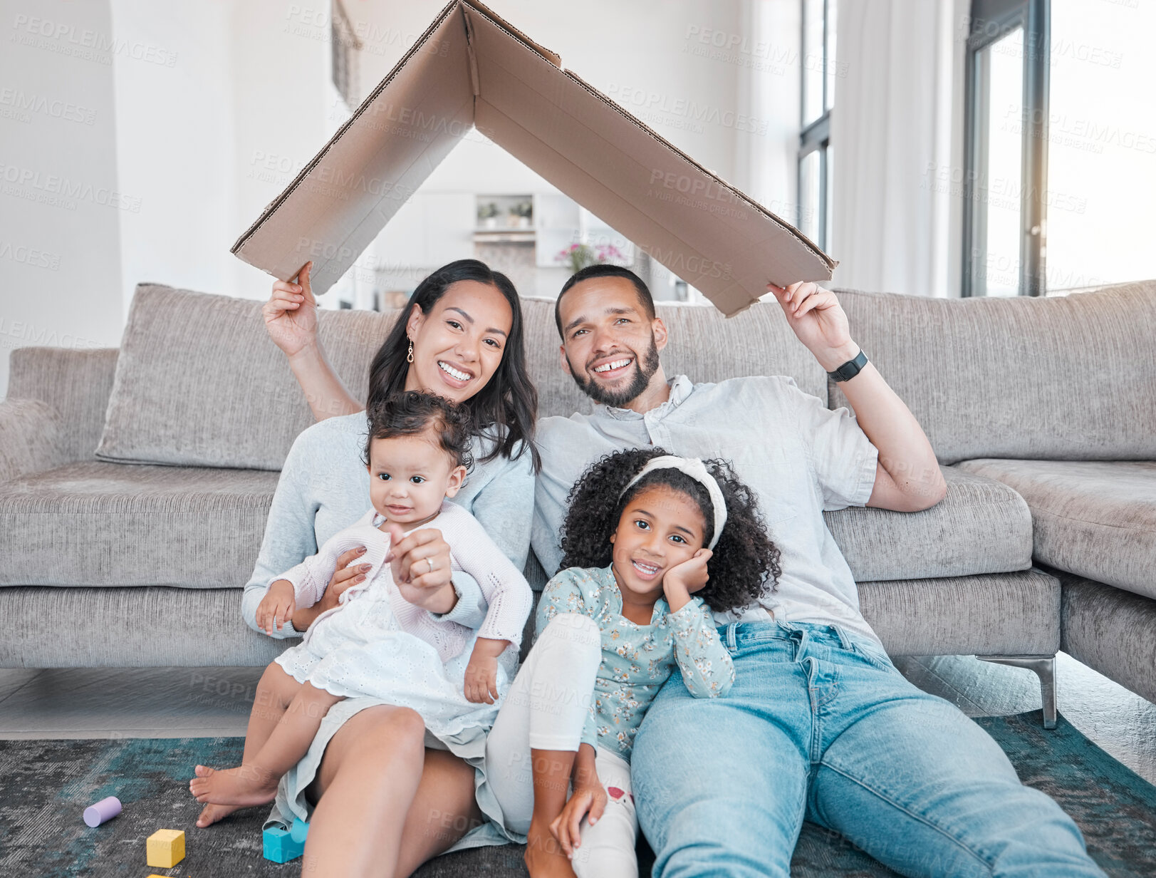 Buy stock photo Family, cardboard roof with home insurance and together in house, love in portrait, unity with mortgage and happy family. Parents, children on living room floor, cover with protection and property.