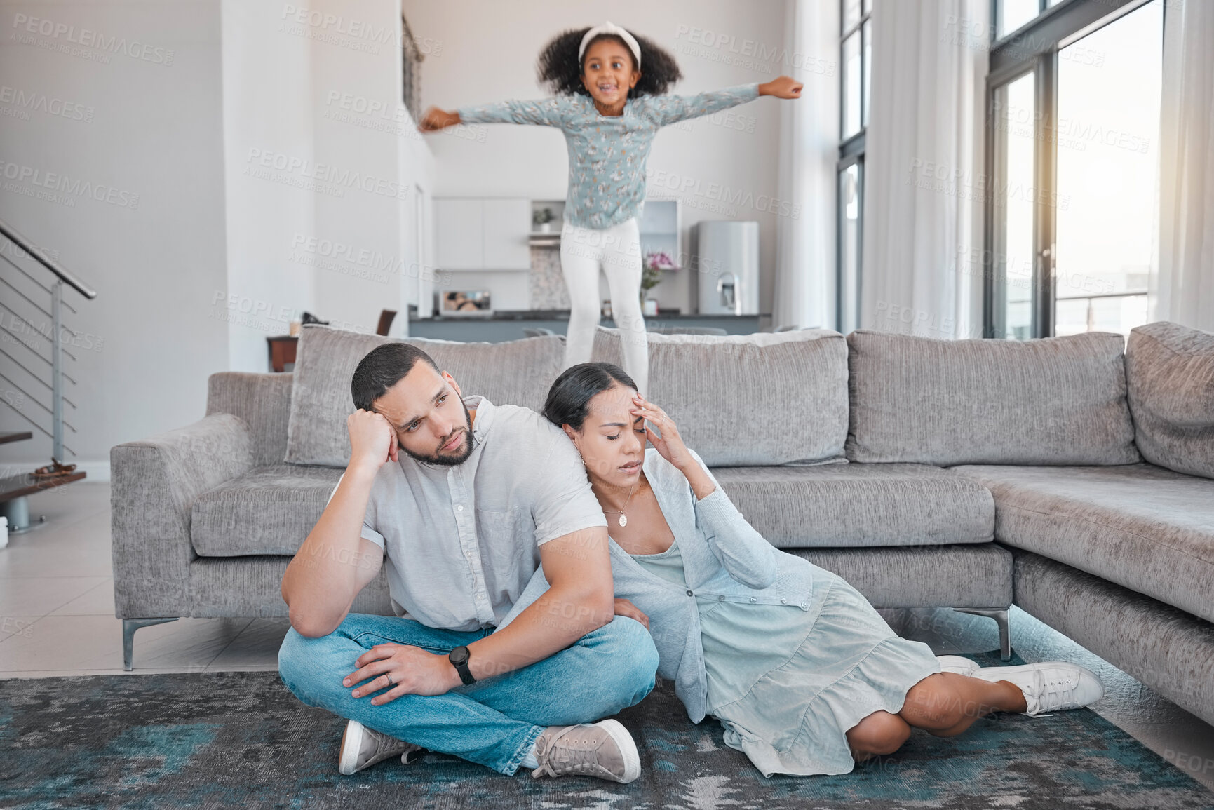 Buy stock photo Tired, parents and child jump on sofa with exhausted mother and father sitting on floor in living room. Family, energy and young girl jumping on couch with frustrated, annoyed and upset mom and dad 