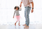 Family, love and father dance with girl, having fun and bonding in home. Smile, happy and parent with child or kid holding hands, playing and dancing, care or enjoying quality time together in house
