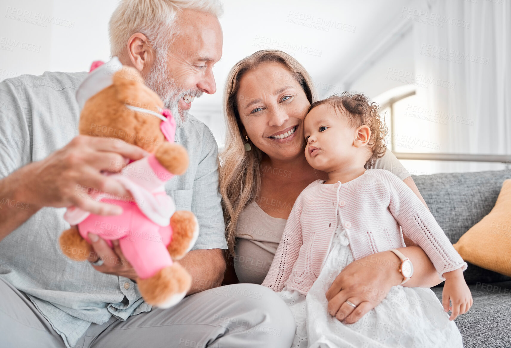 Buy stock photo Children, family and teddy bear with a girl and grandparents playing on the sofa during a visit in their home. Kids, love and toys with a senior man and woman bonding together with their grandchild